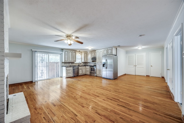 kitchen featuring appliances with stainless steel finishes, ceiling fan, crown molding, sink, and light hardwood / wood-style floors