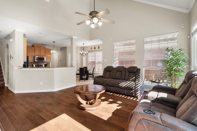 living room featuring ceiling fan with notable chandelier, crown molding, dark hardwood / wood-style flooring, and a high ceiling