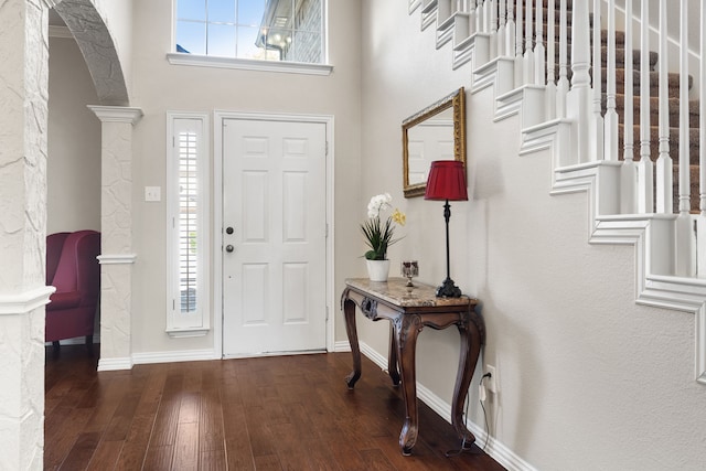 foyer entrance with ornate columns and dark wood-type flooring