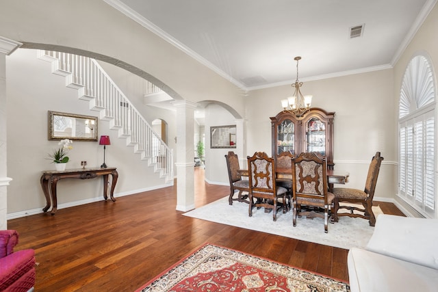 dining room with a notable chandelier, dark hardwood / wood-style flooring, a wealth of natural light, and ornate columns