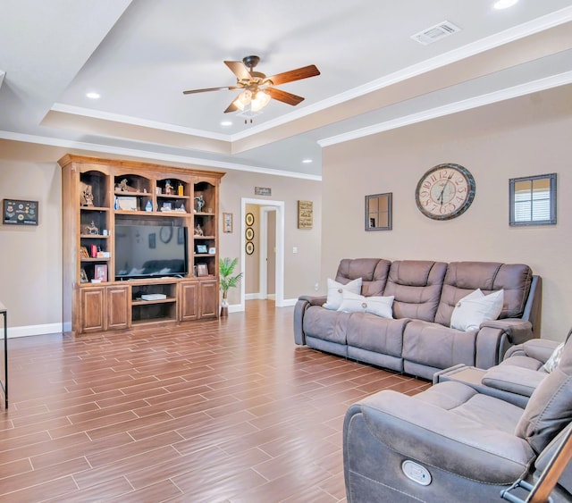 living room with ceiling fan, light hardwood / wood-style floors, crown molding, and a tray ceiling