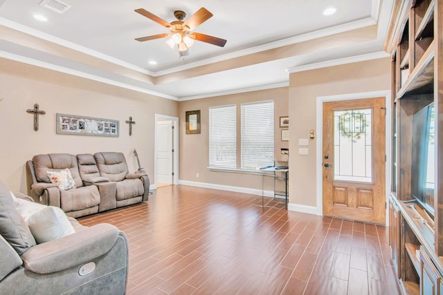 living room featuring hardwood / wood-style floors, ceiling fan, ornamental molding, and a tray ceiling