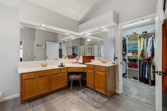 bathroom with hardwood / wood-style floors, vanity, vaulted ceiling, and walk in shower