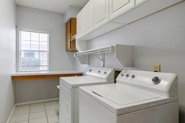 laundry room featuring cabinets, light tile patterned floors, and washer and dryer