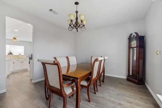 dining area with ceiling fan with notable chandelier and light wood-type flooring