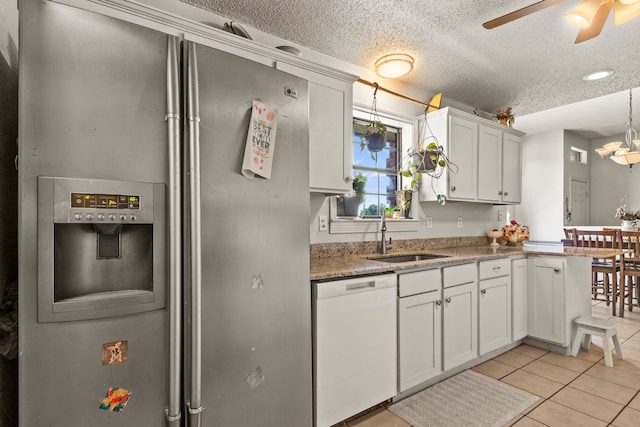 kitchen with white cabinetry, sink, stainless steel fridge, white dishwasher, and light tile patterned floors