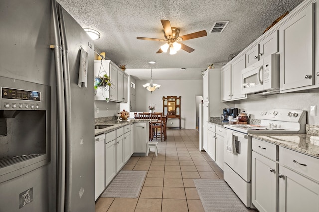 kitchen featuring white cabinets, hanging light fixtures, and white appliances