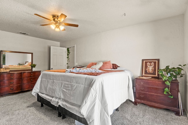 bedroom with ceiling fan, light colored carpet, and a textured ceiling