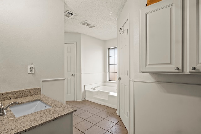 bathroom with vanity, a textured ceiling, tile patterned floors, and a bathtub