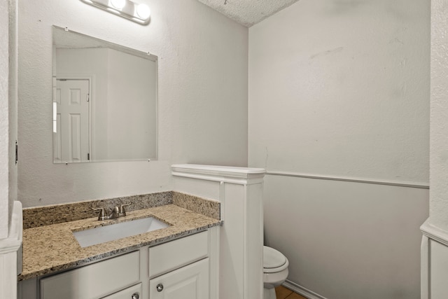 bathroom with vanity, a textured ceiling, and toilet