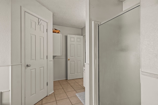 bathroom featuring tile patterned floors, an enclosed shower, and a textured ceiling