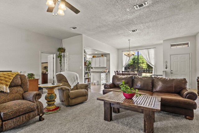 carpeted living room with ceiling fan with notable chandelier and a textured ceiling