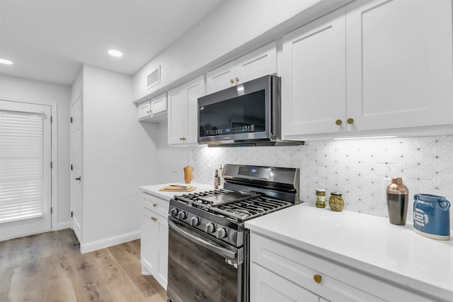 kitchen featuring tasteful backsplash, white cabinetry, stainless steel appliances, and light wood-type flooring