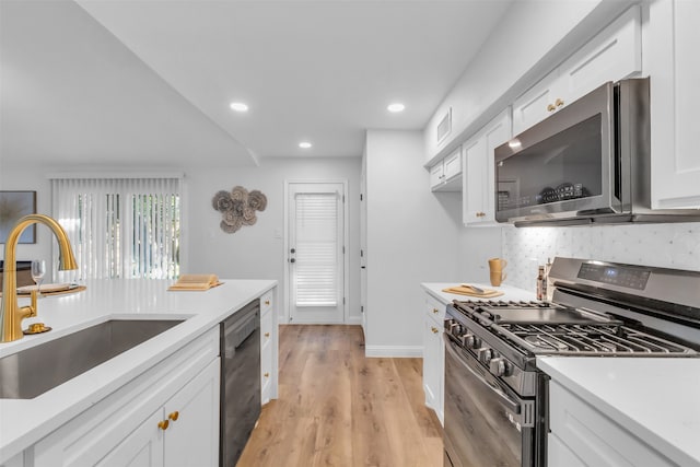 kitchen with white cabinetry, sink, decorative backsplash, appliances with stainless steel finishes, and light wood-type flooring