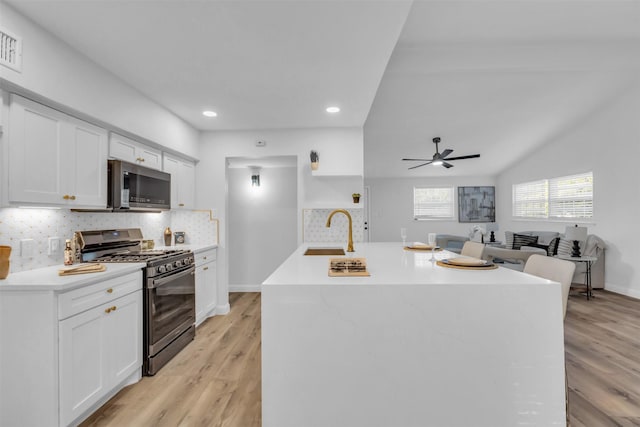 kitchen featuring white cabinets, sink, stainless steel appliances, and a kitchen island with sink