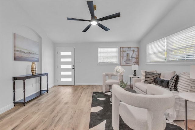 living room with ceiling fan, light hardwood / wood-style flooring, and vaulted ceiling