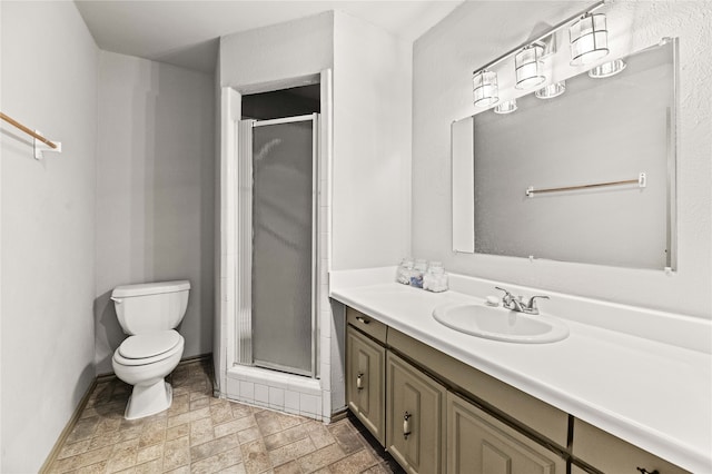 bathroom featuring a shower with door, vanity, and toilet