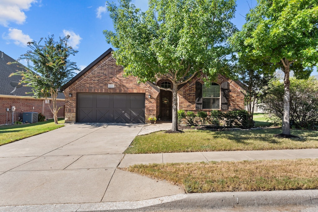 view of front of house featuring cooling unit, a garage, and a front lawn