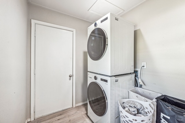 laundry area featuring stacked washer and dryer and light hardwood / wood-style floors