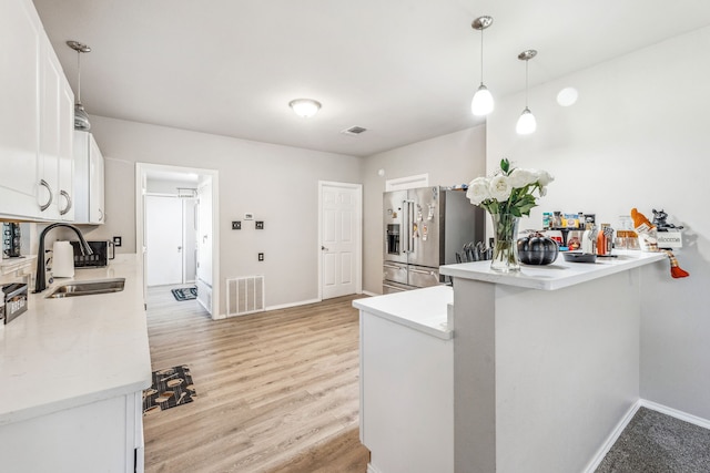 kitchen with kitchen peninsula, high end fridge, sink, light hardwood / wood-style floors, and white cabinetry