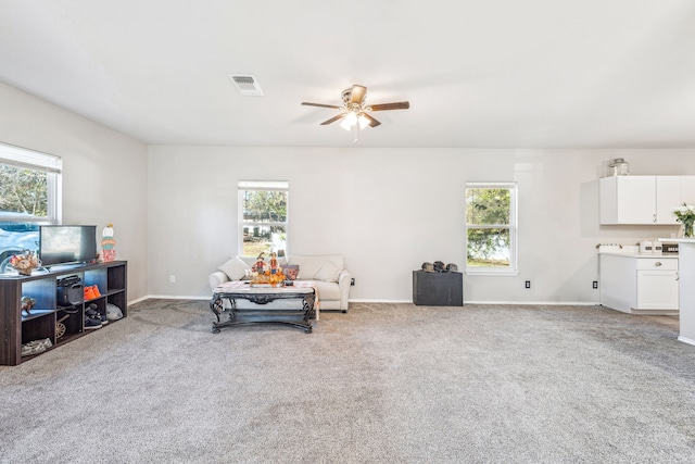 living area with carpet, plenty of natural light, and ceiling fan