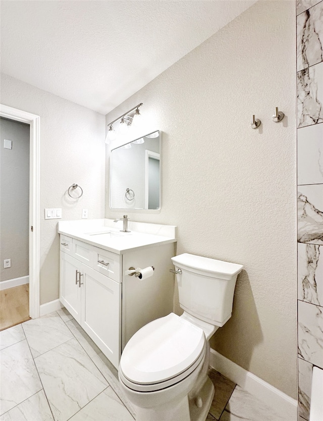 bathroom with vanity, toilet, and a textured ceiling