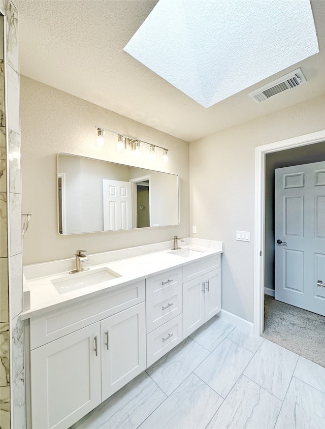 bathroom with a textured ceiling, vanity, and a skylight