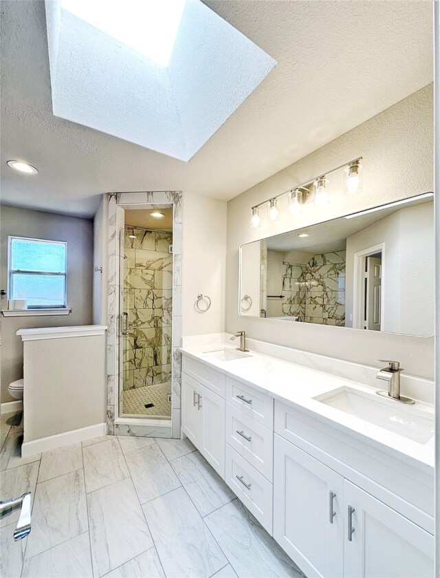 bathroom with a skylight, vanity, an enclosed shower, and a textured ceiling