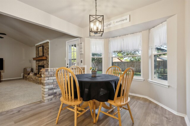 dining room with lofted ceiling, a fireplace, a wealth of natural light, and light hardwood / wood-style flooring