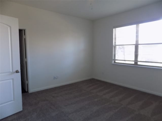 unfurnished room with dark carpet