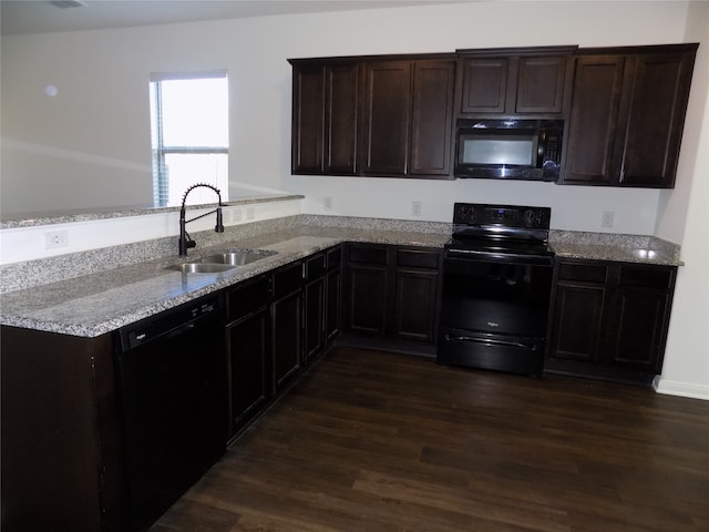 kitchen with kitchen peninsula, light stone counters, dark wood-type flooring, sink, and black appliances