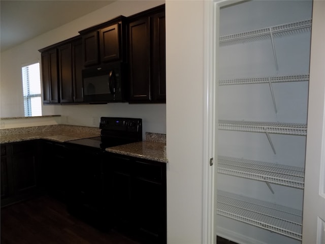 kitchen featuring dark hardwood / wood-style flooring, light stone counters, dark brown cabinetry, and black appliances