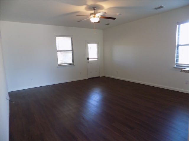 spare room with a wealth of natural light, ceiling fan, and dark hardwood / wood-style floors