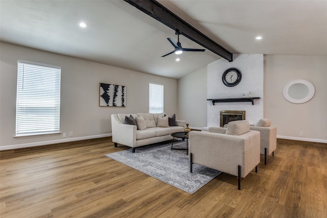 living room with a brick fireplace, lofted ceiling with beams, light hardwood / wood-style flooring, and a healthy amount of sunlight