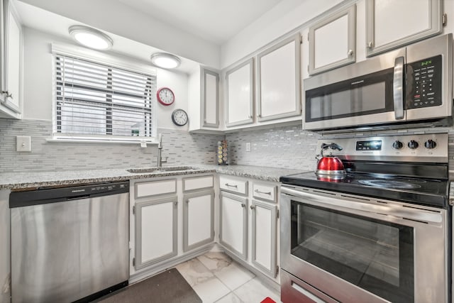 kitchen featuring sink, light stone countertops, tasteful backsplash, white cabinetry, and stainless steel appliances