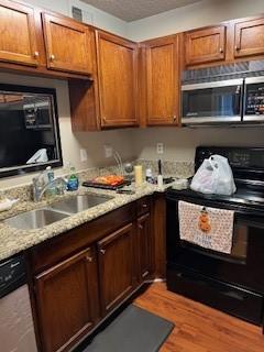 kitchen with black range with electric stovetop, light stone countertops, sink, and wood-type flooring