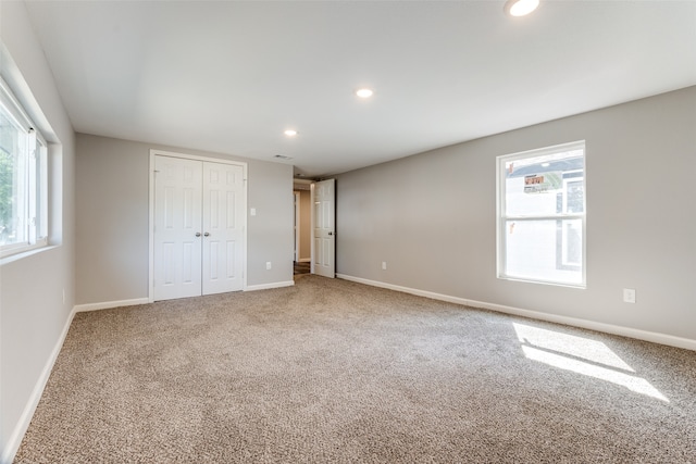 unfurnished bedroom featuring carpet floors, a closet, and multiple windows