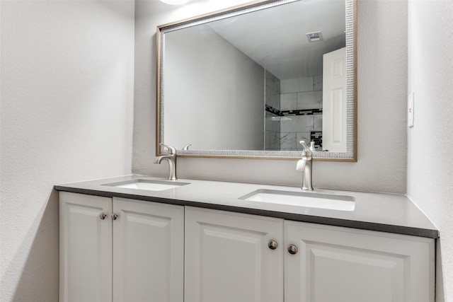 bathroom featuring a tile shower and vanity