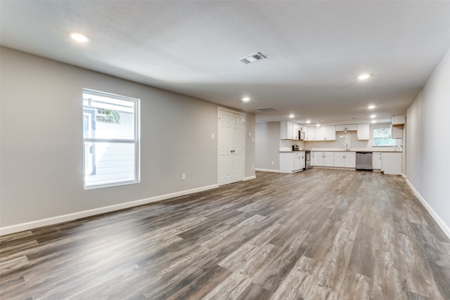 unfurnished living room featuring sink, wood-type flooring, and a textured ceiling