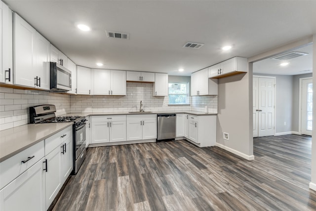 kitchen featuring white cabinetry, sink, dark wood-type flooring, stainless steel appliances, and backsplash