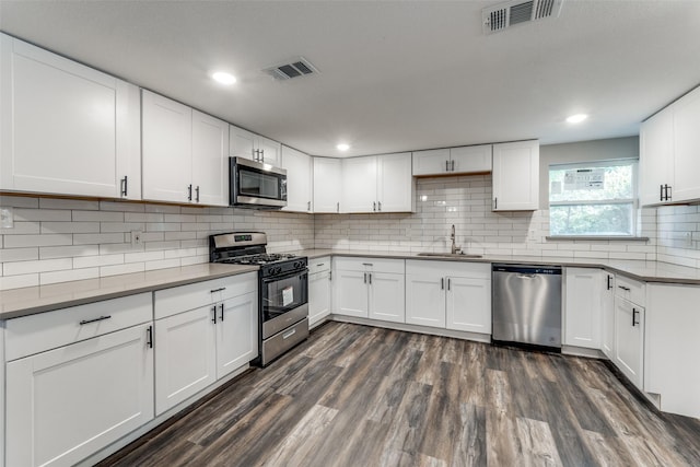 6614 Parkdale Dr, Dallas, TX 75227 - kitchen featuring appliances with stainless steel finishes, a sink, dark wood finished floors, backsplash, and recessed lighting