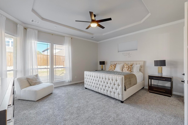 carpeted bedroom with ceiling fan, a raised ceiling, and ornamental molding