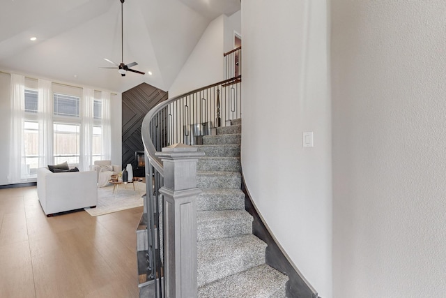 stairway with hardwood / wood-style flooring, high vaulted ceiling, and ceiling fan