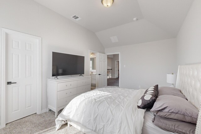 bedroom featuring light carpet, connected bathroom, and vaulted ceiling