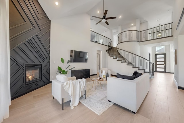 living room featuring ceiling fan, high vaulted ceiling, and light hardwood / wood-style floors