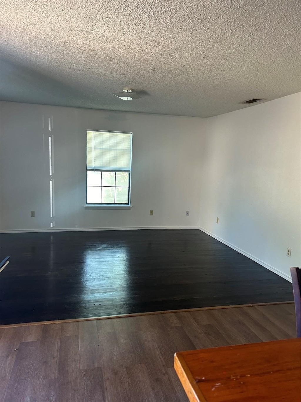 empty room featuring a textured ceiling and dark wood-type flooring