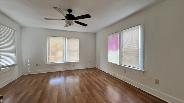 spare room with dark hardwood / wood-style flooring, ceiling fan, and a healthy amount of sunlight