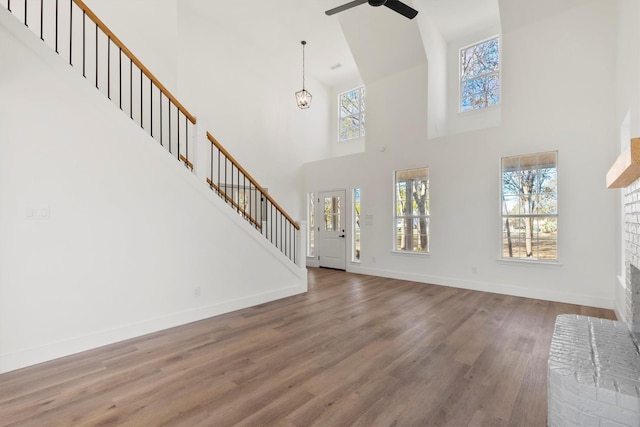 unfurnished living room featuring hardwood / wood-style flooring, ceiling fan with notable chandelier, and a fireplace