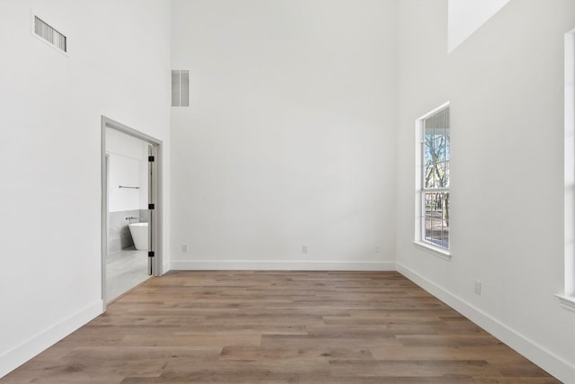 spare room with light hardwood / wood-style flooring and a high ceiling