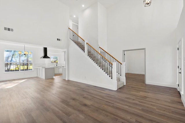 unfurnished living room featuring a notable chandelier, a towering ceiling, and dark hardwood / wood-style floors